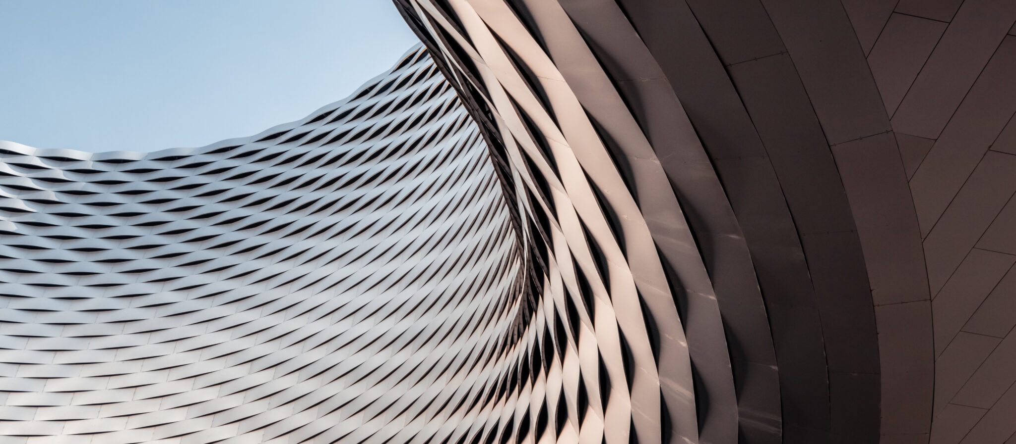 An architecturally unique curved building set against a clear blue sky.